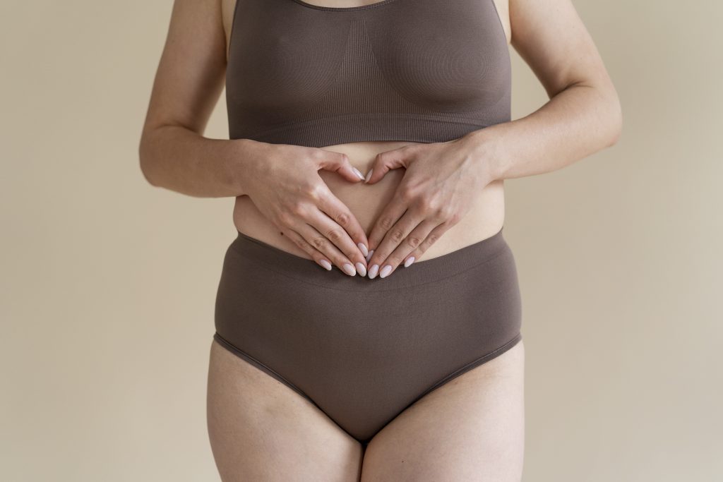 Mains posées sur le ventre en forme de cœur, symbolisant la connexion entre le ressenti émotionnel et la sphère digestive.